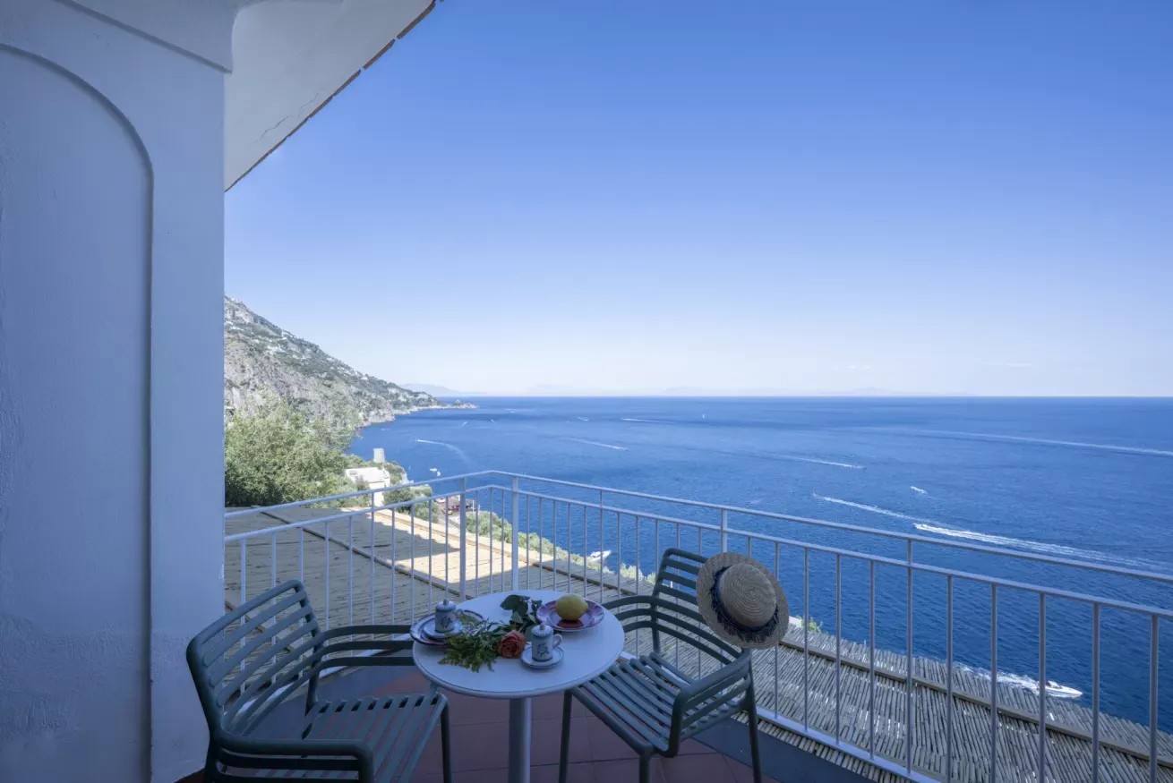 Balcone con tavolo apparecchiato affacciato sul mare e sulla costa rocciosa