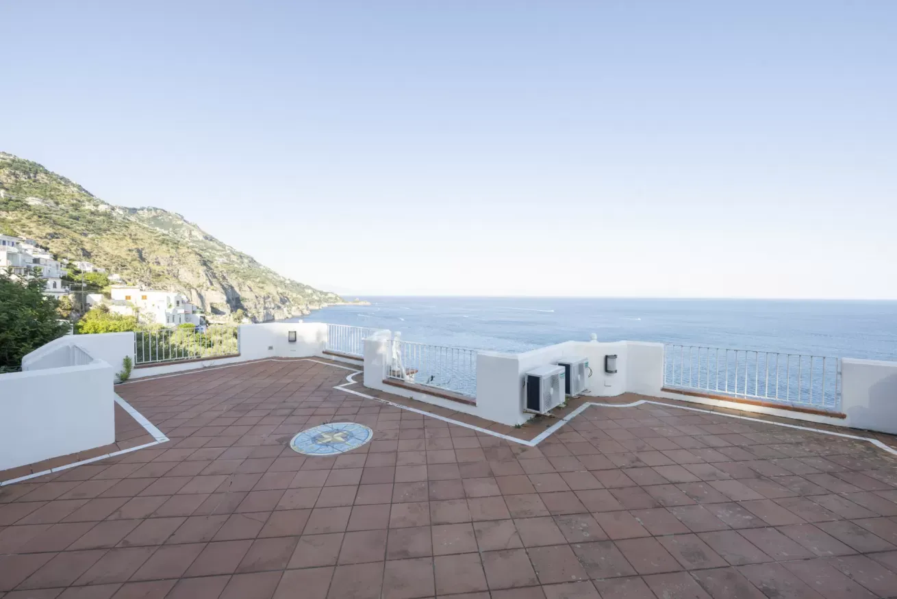 Terrazza panoramica sul mare con vista sulla costa rocciosa e sulle case arroccate sulla collina